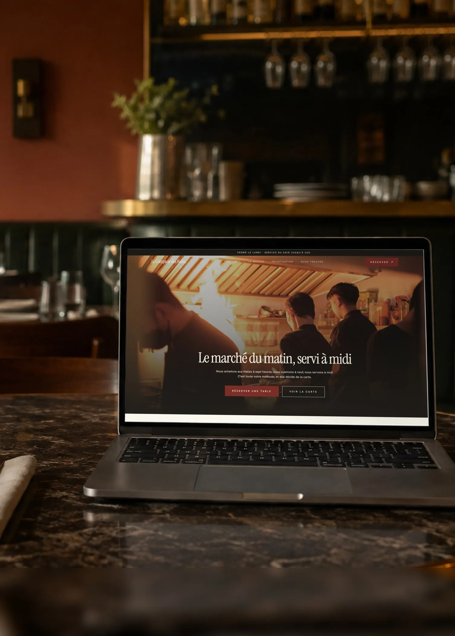 Ambiance table : le site d'un bistrot de Bayonne, affiché sur un ordinateur portable posé sur une table de marbre, dans la salle