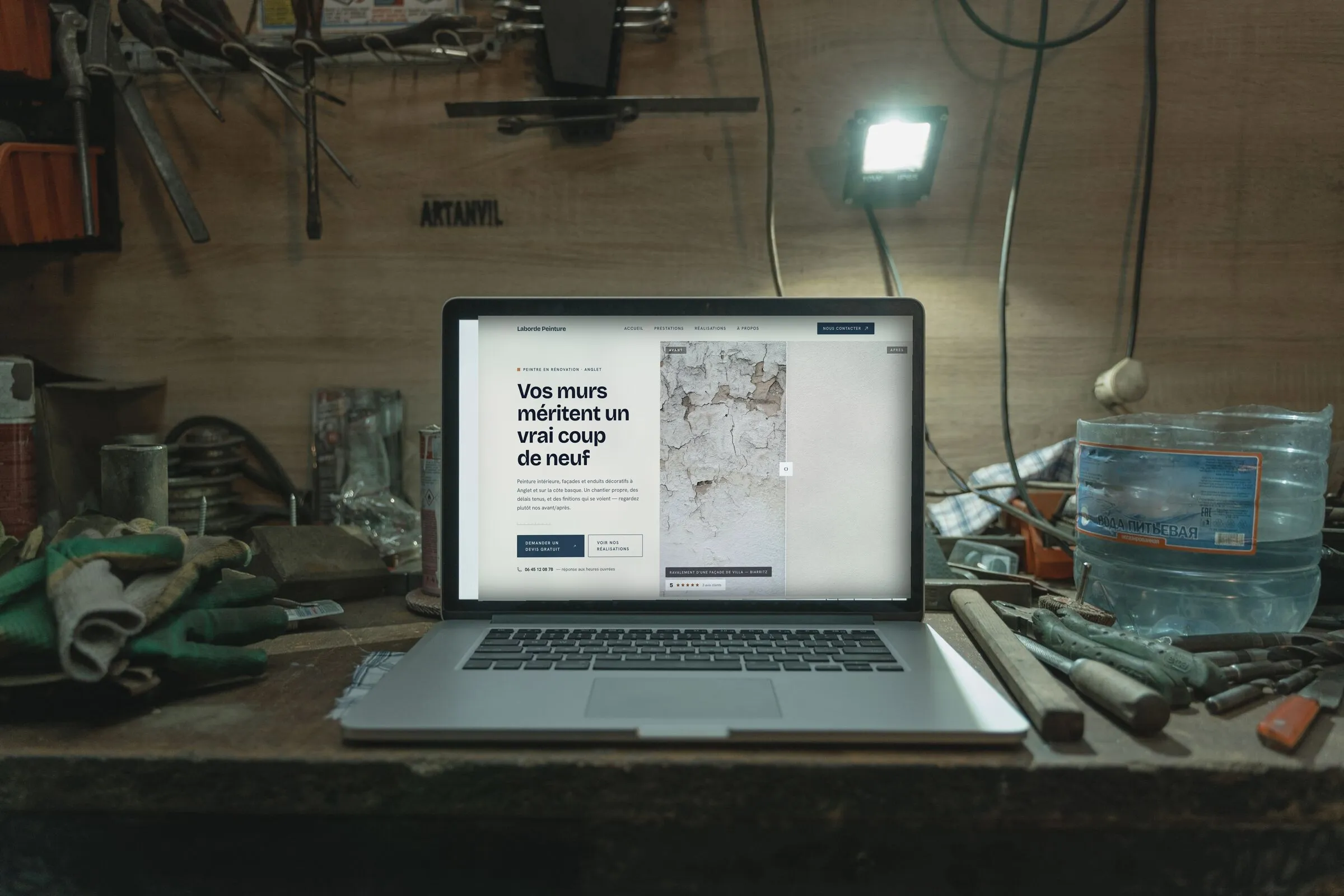 Le site d’un peintre en rénovation affiché sur un ordinateur portable posé sur un établi d’atelier