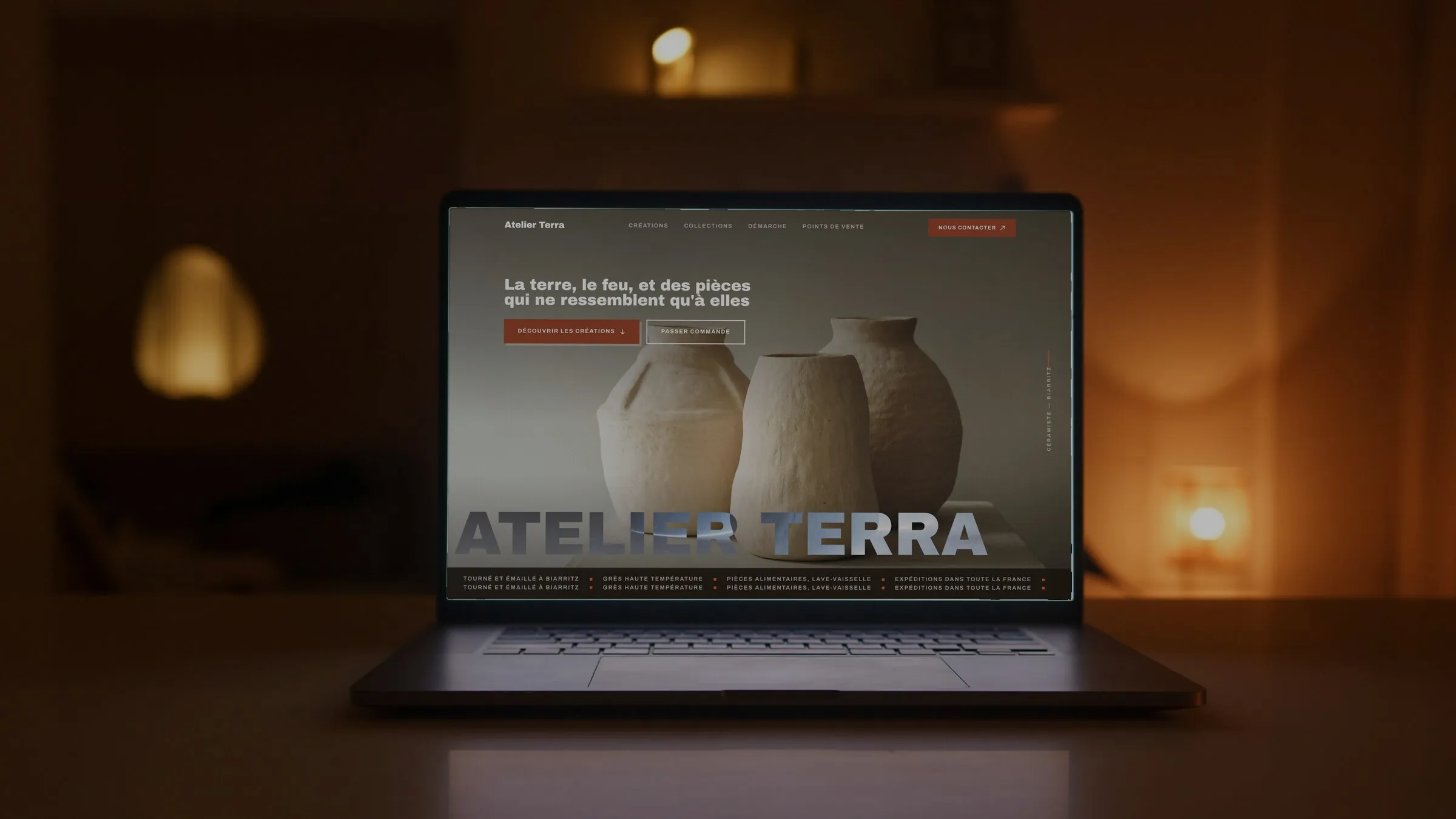 Le site d’une céramiste affiché sur un ordinateur portable, dans une pièce éclairée à la bougie