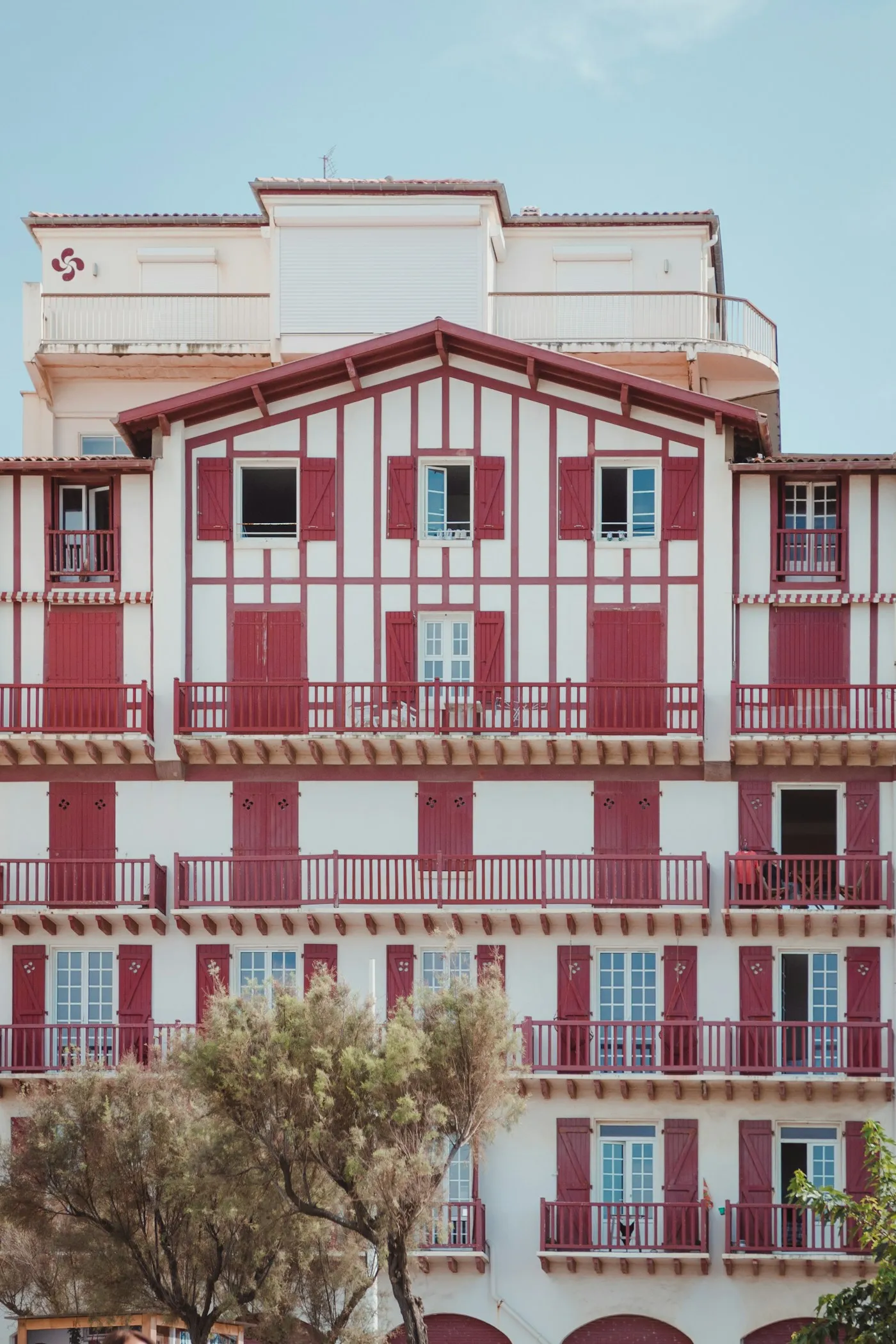Façade d’une maison basque blanche à colombages et volets rouges