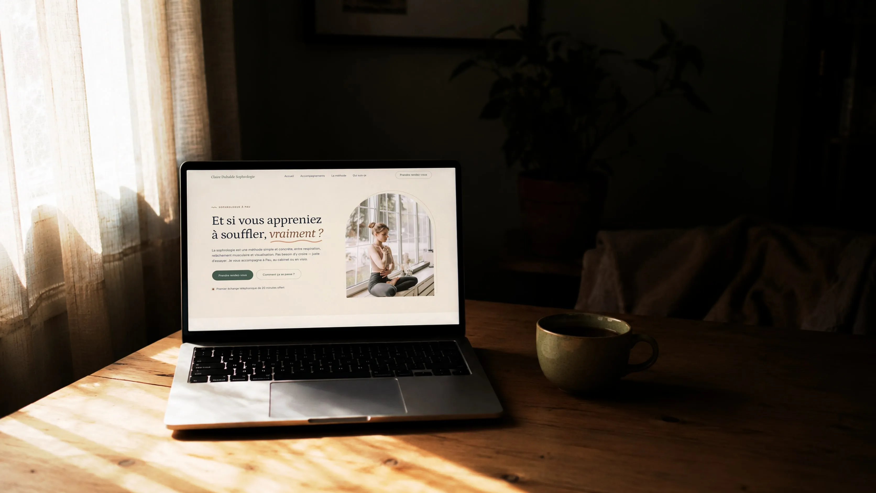 Le site d’une sophrologue affiché sur un ordinateur portable, devant une fenêtre voilée
