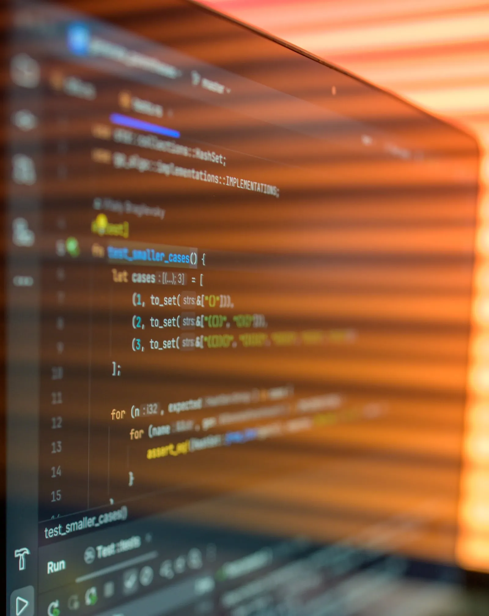 Gros plan sur un écran affichant du code, rayé par la lumière chaude d’un store.